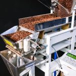pexels-photo-4820820 Close-up of coffee beans in an industrial roasting machine with a control panel.